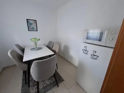 a small kitchen with a table and a refrigerator at Apartman Mint in Bihać