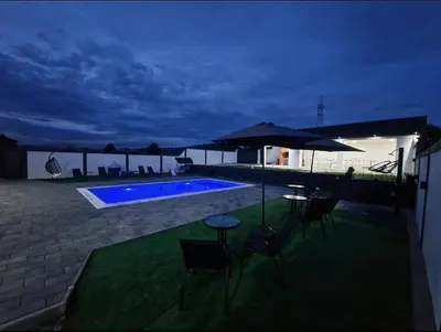 a patio with chairs and an umbrella and a swimming pool at Villa Dunja Prijedor in Prijedor