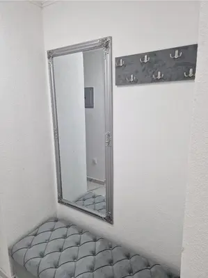 a mirror on a wall with a ottoman in a room at Villa Dunja Prijedor in Prijedor