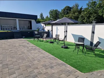 a lawn with chairs and tables and umbrellas at Villa Dunja Prijedor in Prijedor