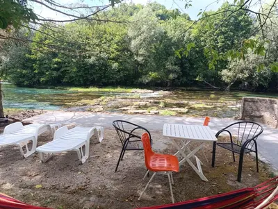 a group of chairs and tables next to a river at River Nest in Kulen Vakuf
