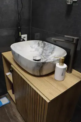 a bathroom sink sitting on top of a wooden counter at Om relax in Prijedor