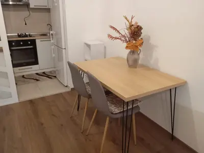 a wooden table with two chairs and a vase with flowers at ALEXiS in Modriča