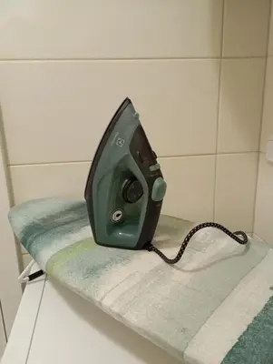 a green iron sitting on top of a towel at ALEXiS in Modriča