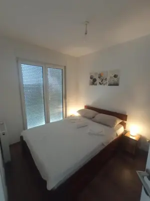 a white bed in a bedroom with two windows at ALEXiS in Modriča