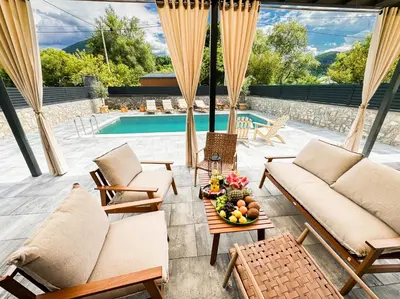 a patio with couches and a table with a bowl of fruit at Villa Aurelia Wellness in Illidža
