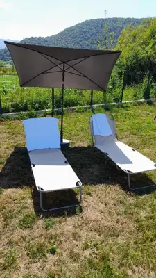 two lounge chairs and an umbrella in a field at Nature flow Bihac in Otoka