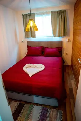a red bed in a small room with a window at Seosko Domaćinstvo Protic , Prijedor , Veliko Palančište in Velika Palančište