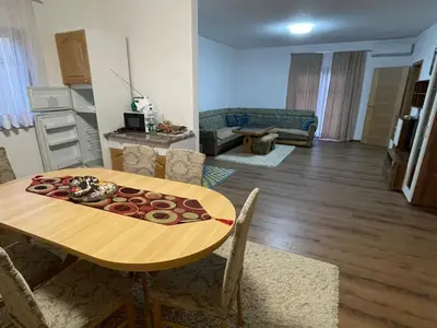 a living room with a wooden table and a dining room at EDina Apartman in Bihać