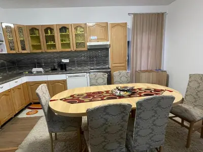 a kitchen with a wooden table with chairs and a tableasteryasteryasteryasteryastery at EDina Apartman in Bihać