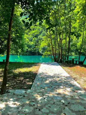 a path in a park with two benches and a lake at UNA Dream in Bihać