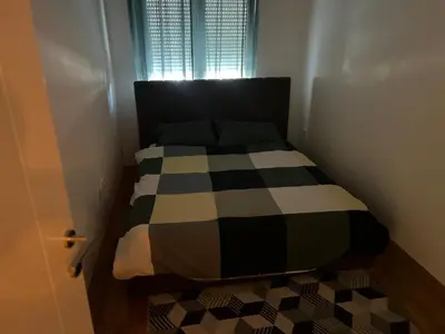 a small bedroom with a bed with a checkered floor at Apartman Perfectroom in Ivišovo Greblje