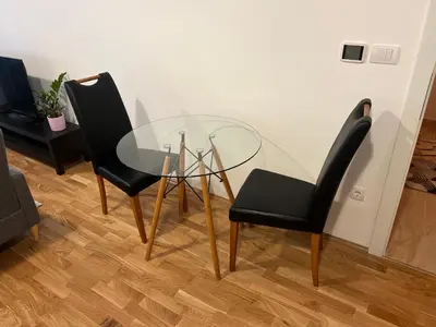 a glass table and two black chairs in a room at Apartman Perfectroom in Ivišovo Greblje