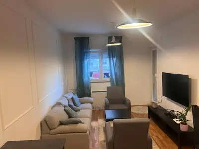 a living room with a couch and two chairs and a television at Apartman Perfectroom in Ivišovo Greblje