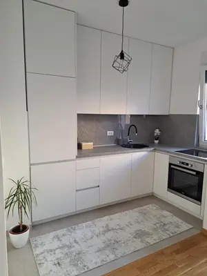 a kitchen with white cabinets and a potted plant at Apartman Luxury kod Kafeterije 5 i Wabi Sabi in Banja Luka