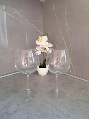 two wine glasses sitting next to a vase with a flower at Apartman Luxury kod Kafeterije 5 i Wabi Sabi in Banja Luka