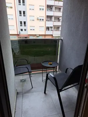 a balcony with two chairs and a table and a building at Apartman Luxury kod Kafeterije 5 i Wabi Sabi in Banja Luka