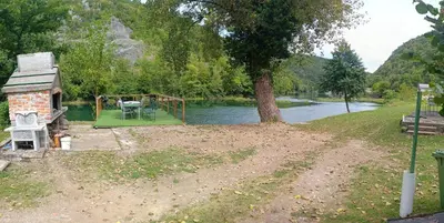 a house with a table and a playground next to a river at Holiday home Una in Bosanska Krupa