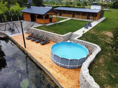 a hot tub on a wooden deck next to a house at Una Hacienda in Bihać