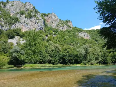 a river with trees and a mountain in the background at Max in Bihać