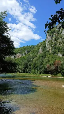 a river with trees and a mountain in the background at Max in Bihać