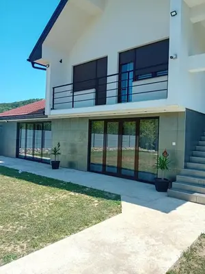 a large building with glass doors and potted plants at Vikendica Šapat Sane, Prijedor