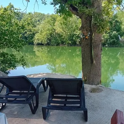 two chairs and a table next to a lake at Vikendica Šapat Sane, Prijedor