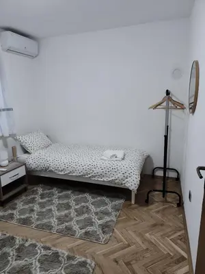 a white room with a bed and a mirror at Apartman Lidija in Bihać