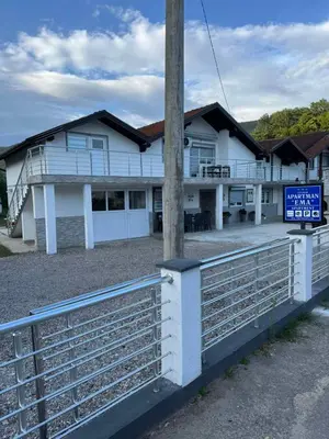 a white building with a fence in front of it at Apartman Studio EMA in Orašac