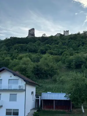 a white house in front of a hill with two towers at Apartman Studio EMA in Orašac
