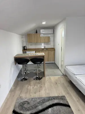 a kitchen with a table and two stools in a room at Apartman Studio EMA in Orašac