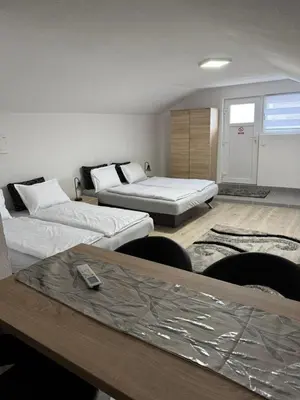 a room with two beds and a table with chairs at Apartman Studio EMA in Orašac