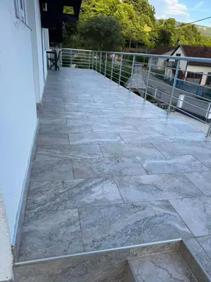 a patio with a stone floor and a fence at Apartman Studio EMA in Orašac