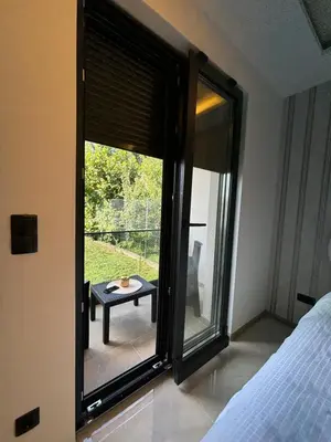 a bedroom with a large window with a table outside at Villa Aurea in Bihać