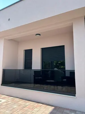 a living room with black furniture and windows at Villa Aurea in Bihać