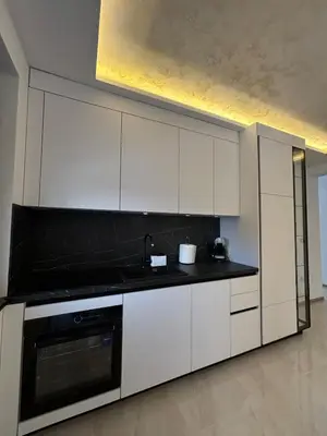 a kitchen with white cabinets and a black counter top at Villa Aurea in Bihać