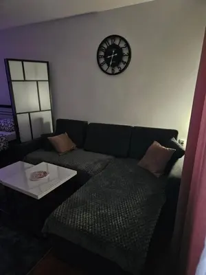 a living room with a couch and a clock on the wall at Apartman Maja in Bosanski Šamac