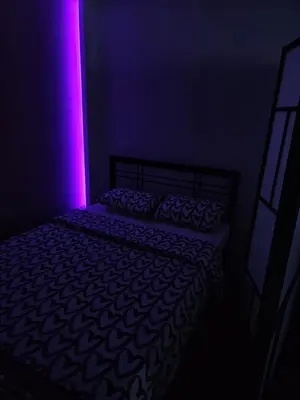 a dark room with a bed with a purple light at Apartman Maja in Bosanski Šamac