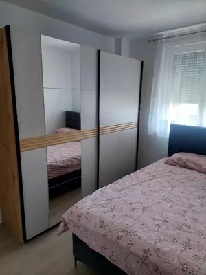 a bedroom with a bed and a closet with a mirror at Apartman Sofia Doboj in Doboj