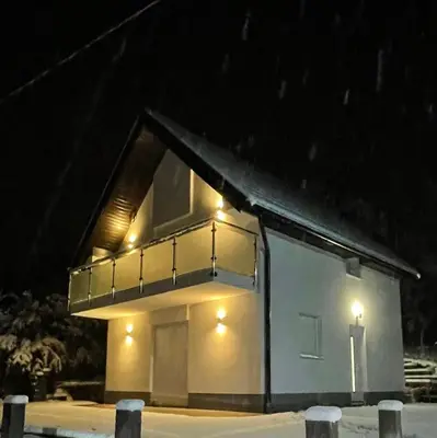 a house with a balcony in the snow at night at Vikendica Dijana Ramsko jezero