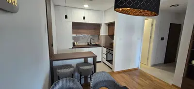 a kitchen with white cabinets and a table and stools at Apartment Lazarus with garage Banja Luka in Banja Luka
