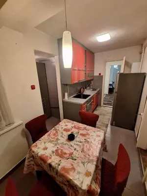 a small kitchen with a table and red chairs at Nova varos apartman in Banja Luka