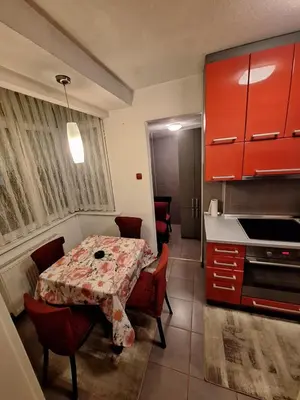 a kitchen with a table and red cabinets at Nova varos apartman in Banja Luka