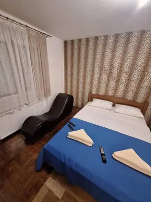 a bedroom with a blue bed and a chair at Nova varos apartman in Banja Luka