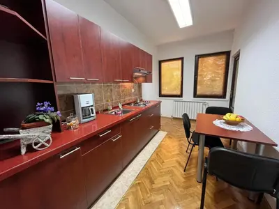 a kitchen with wooden cabinets and a dining room table at StayBihac in Bihać