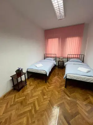 a room with two beds and a wooden floor at StayBihac in Bihać