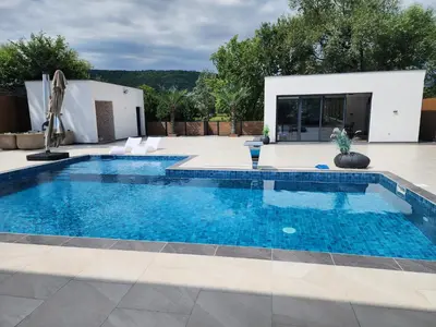 a swimming pool with blue water in a yard at La Villa Luxury Home Bihac in Bihać