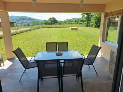 a table and chairs on a patio with a view of a field at Holiday home Biskupici in Visoko