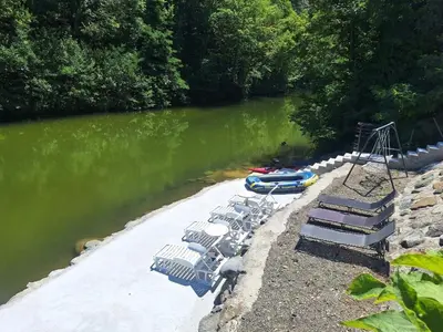 a group of chairs and a swing on a river at Apartmani Vanilla in Zavidovići
