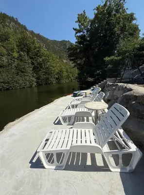 a row of white chairs and tables next to a river at Apartmani Vanilla in Zavidovići